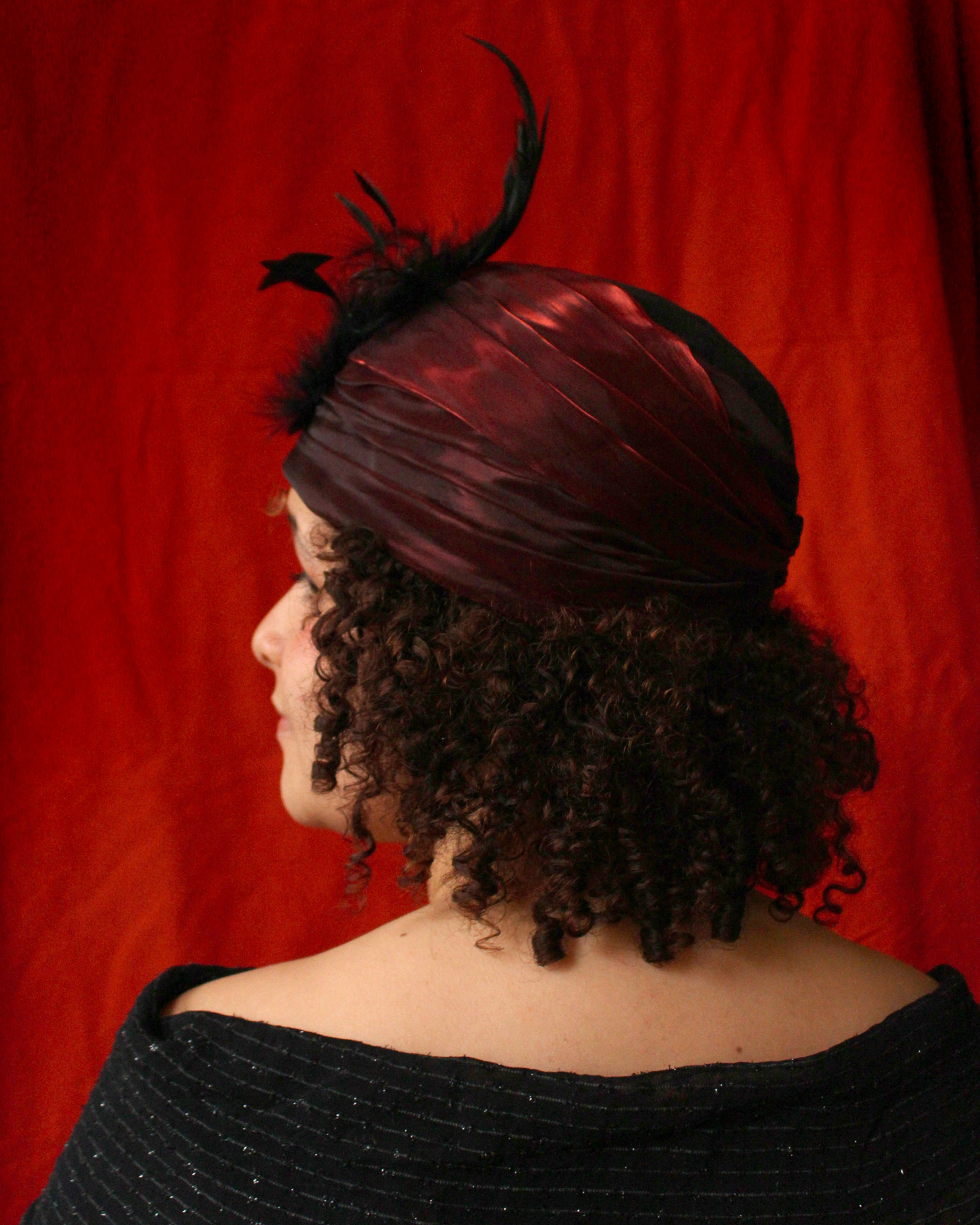 A photo which is a side view of the above turban. From this angle you can better see the way the rooster feathers curve forwards and inwards.