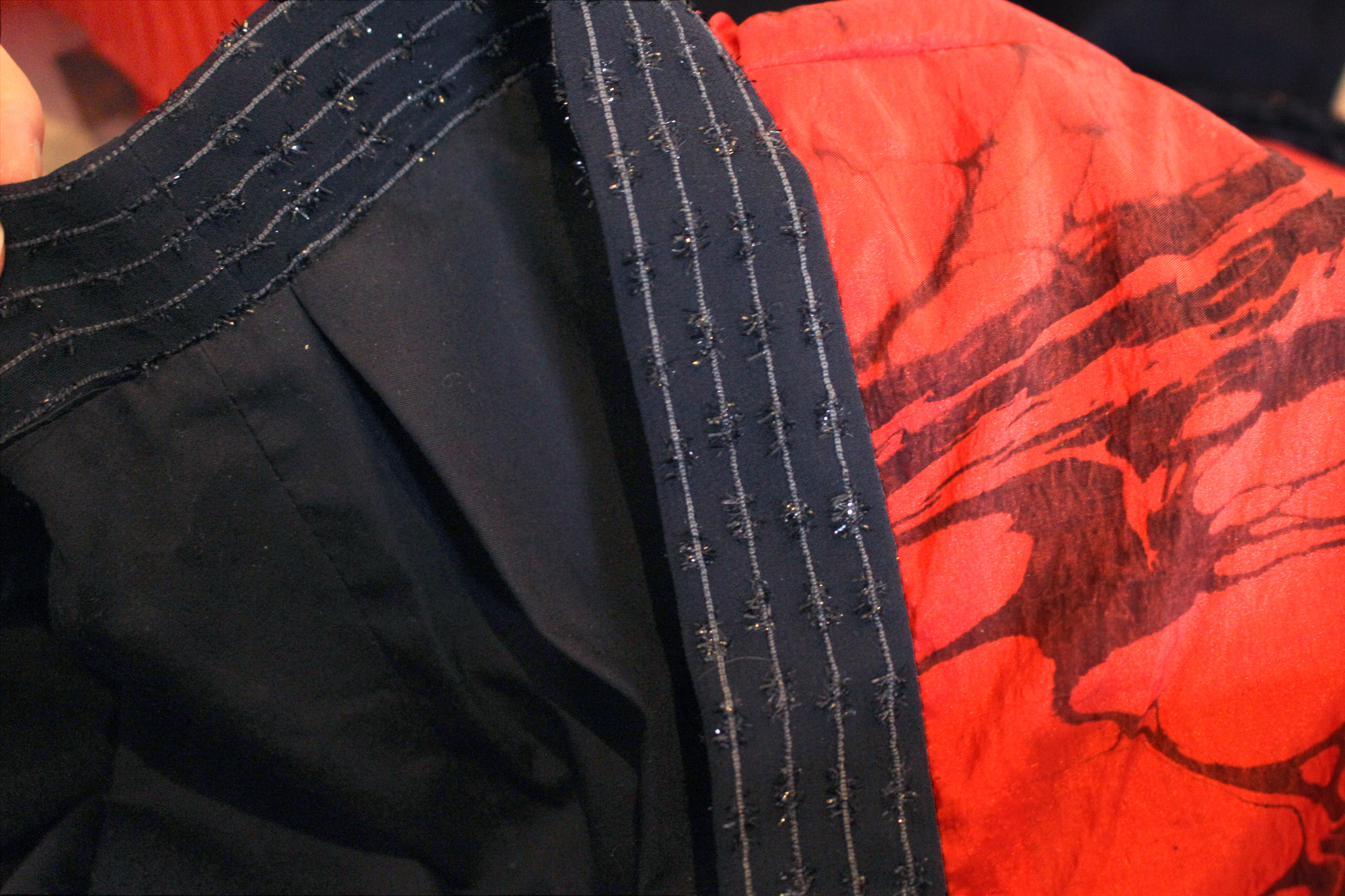 A close up photo of the opera coat which shows the marble detail on its shoulder, the fabric of the collar, and the black lining.